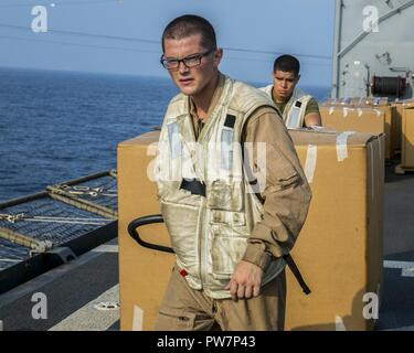 Stati Uniti Quinta Flotta AREA DI OPERAZIONI (sett. 24, 2017) - Lance Cpl. Jamie Robbins e Lance Cpl. Miguel Garcia, combattere Cargo Marines a bordo della USS Pearl Harbor (LSD 52), il trasporto di materiali di consumo che sono stati consegnati durante un rifornimento in mare (RAS) con Lewis e Clark-secco classe nave cargo USNS Washington Camere (T-AKE 11).. Xv Marine Expeditionary Unit è intrapreso l'America anfibio gruppo pronto e viene distribuito per mantenere la sicurezza regionale negli Stati Uniti Quinta Flotta area di operazioni. Foto Stock