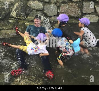 Lancia Cpl. Evan C. DELTA NAT GAS si impegna in attività in acqua con i bambini da Asunaro Highashi, un vivaio a Okinawa, Giappone, Sett. 28, 2017. Il vivaio Marines invita a partecipare alle attività settimanali con i bambini per stabilire un legame tra la generazione più giovane di Okinawa e gli Stati Uniti Militari. Delta nat gas è una lima, Ohio native e ingegnere di combattimento con Combat Assault battaglione, terza divisione Marine. Foto Stock