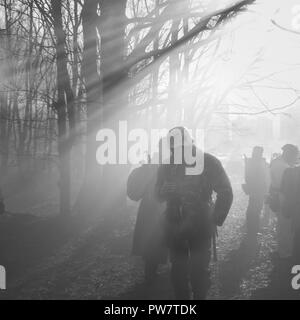 Re-enactors vestito come il tedesco della Wehrmacht Soldato di fanteria nella guerra mondiale II in piedi nella retroilluminazione drammatico attraverso il fumo durante la rievocazione storica. P Foto Stock