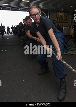 Mar dei Caraibi (sett. 26, 2017) velisti assegnati all'assalto anfibio nave USS Wasp (LHD 1) heave intorno a una linea in hangar bay durante un rifornimento in mare. Vespa è al largo dell'isola di Dominica fornendo aiuti per gli sfollati come parte della prima risposta sforzi nella scia di uragano Maria. Il Dipartimento della difesa è di sostenere gli Stati Uniti Agenzia per lo Sviluppo Internazionale (USAID), il piombo agenzia federale, per aiutare le persone colpite dall'uragano Maria per ridurre al minimo la sofferenza ed è un componente del complessivo intero-di-risposta del governo sforzo. Foto Stock