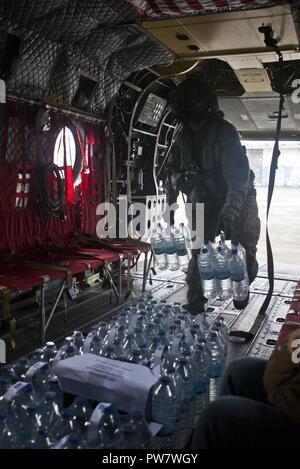 Stati Uniti Army Sgt. Delton Reynolds, un elicottero capo equipaggio con Joint Task Force - Isole Sottovento, carichi di acqua su un CH-47 elicottero Chinook A la Pointe-à-Pitre Aeroporto Internazionale di Pointe-à-Pitre, Guadalupa, Sett. 29, 2017. L'elicottero acqua erogata per essere distribuiti a persone in stato di bisogno all'Douglas-Charles Aeroporto di Melville Hall, Dominica. Su richiesta dei paesi partner e il Dipartimento di Stato e gli Stati Uniti Agenzia per lo Sviluppo Internazionale, JTF-li ha distribuito degli aerei e i membri del servizio ad aree nella zona orientale del Mar dei Caraibi colpiti dagli uragani di Irma e Maria Foto Stock