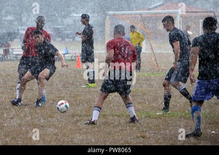Soldati assegnato al XXV divisione di fanteria della brigata sessantacinquesimo Engineer Battaglione, 2° Brigata Team di combattimento e 2a Bn., 35th Inf. Reggimento, 3° BCT, giocare in acquazzone durante il Tropic Lightning settimana del torneo di calcio a Schofield Barracks, Hawaii, il 2 ottobre, 2017. Tropic Lightning settimana è un giro evento sportivo per commemorare il 76° anniversario della divisione. Foto Stock