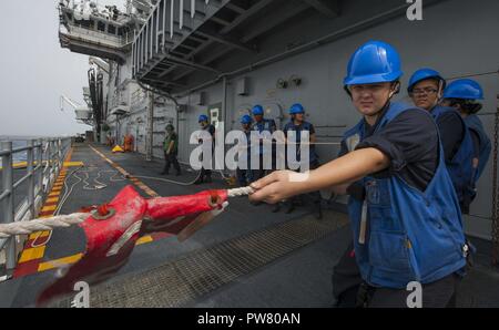 Mar dei Caraibi (sett. 26, 2017) velisti assegnati all'assalto anfibio nave USS Wasp (LHD 1) heave intorno a una linea durante un rifornimento in mare con il combattimento veloce nave appoggio USNS alimentazione (T-AOE-6). Vespa è al largo dell'isola di Dominica fornendo aiuti per gli sfollati come parte della prima risposta sforzi nella scia di uragano Maria. Foto Stock