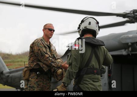 U.S Marine Il Mag. Robert Gill, dell'ufficiale responsabile della Joint Task Force - Sottovento isola l'elemento di sicurezza, raccoglie i caschi di volo da un marinaio negli Stati Uniti con un elicottero di combattimento di mare Squadron 22 per dare ai cittadini degli Stati Uniti uscire Dominica a Charles-Douglas Aeroporto di Melville Hall, Dominica, Sett. 25, 2017. Gill e il suo Marines garantiscono la sicurezza e la stabilità in corrispondenza di zone di sbarco e presso l'U.S. Il dipartimento di stato di evacuazione del centro di controllo in aeroporto. Su richiesta dei paesi partner e il Dipartimento di Stato e gli Stati Uniti Agenzia per lo Sviluppo Internazionale, JTF-li ha distribuito gli aeromobili Foto Stock