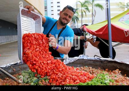 Alejandro Torres, uno chef volontariato con una organizzazione non-profit World cucina centrale, prepara un piatto per i residenti a José Miguel Agrelot Coliseum in San Juan, Puerto Rico, Ottobre 3, 2017. WCK preparati per alimentare circa 46.000 residenti. Lo Chef Jose Andres, il fondatore di WCK, supportato la Federal Emergency Management Agency aiutando coloro che sono colpiti dall uragano Maria per ridurre al minimo la sofferenza come parte del complessivo intero-di-risposta del governo sforzi. Foto Stock