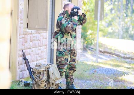 Stati Uniti Army Spc. Johnny lungo, assegnato a U.S. Esercito Cyber comando, fissa la sua maschera protettiva prima di cancellare simulata selezionata labortories chimica durante il 2017 miglior guerriero concorrenza sul Fort A.P. Hill, Va., Ottobre 4, 2017. La BWC è un giro annuale evento che si prova di 22 soldati da 11 principali dei comandi sul loro le capacità fisiche e mentali. Foto Stock