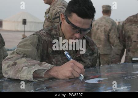 1Lt. Christopher Duncan della sede centrale e sede società, 2° Battaglione, 7° reggimento di cavalleria, 3° Brigata corazzate contro la squadra, 1° Divisione di cavalleria aggiunge la sua firma su un pannello di esperti di Fante titolari di badge a Camp Buehring, Kuwait, 1 ottobre, 2017. I 220 candidati che hanno iniziato il crogiolo 29 ha guadagnato il badge ambita, che li identifica come esperti nel loro campo di carriera. Foto Stock