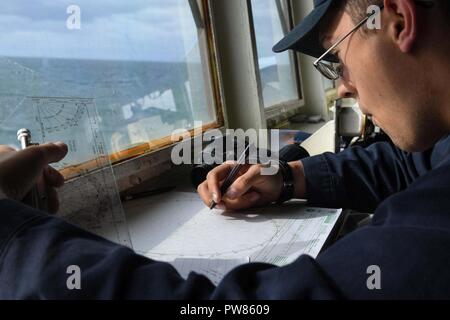 Oceano atlantico (ott. 5, 2017) Ensign Walter Brobson, dalla Sierra Vista, Arizona, completa una scheda di manovra, mentre è di guardia a bordo del Arleigh Burke-class guidato-missile destroyer USS Donald Cook (DDG 75) durante l'esercizio comune della Warrior 17-2, il 5 ottobre 2017. Joint Warrior è un REGNO UNITO-led, esercizio di multinazionali che sviluppa l'interoperabilità e la cooperazione in tutte le aree di guerra. Foto Stock