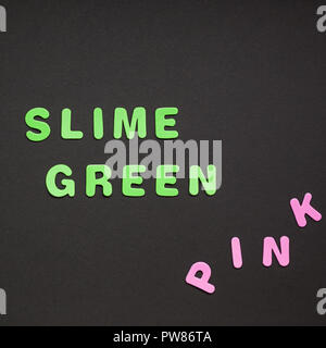 Creative testo colorato in plastica lettere Slime scritta Verde su nero lo sfondo della carta con copia spazio. Colore alla moda concetto blogger template Foto Stock