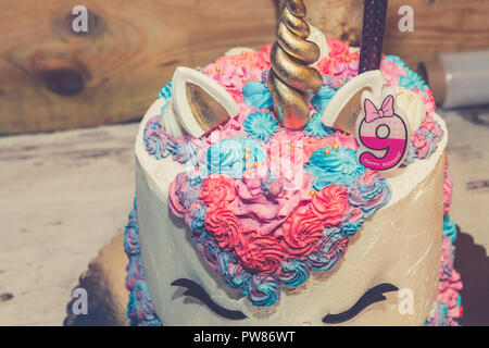 Unicorn torta di compleanno per bambine decorata con colorate di panna montata e il numero nove sulla parte superiore. Close up. Foto Stock