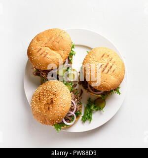 Tirato hamburger di manzo con verdure sulla piastra bianca su sfondo di pietra. Vista superiore Foto Stock