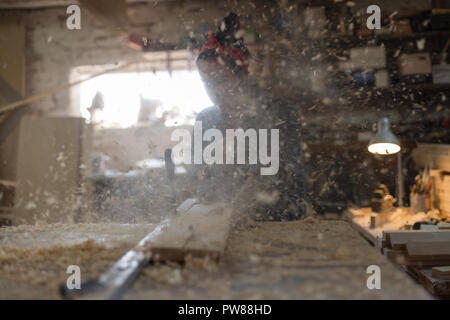 Donna artigiano sta lavorando su una sega in un workshop di legno. Mani femminili vide il pannello di legno. Foto Stock