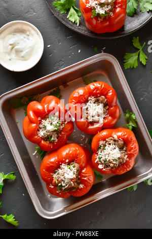 Farcite i peperoni rossi con carne macinata, riso, cipolla, formaggio parmigiano sulla pietra nera dello sfondo. Vista superiore Foto Stock