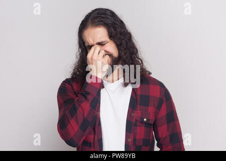 Ritratto di pianto triste uomo con barba nera e lunghi capelli ricci in stile casual, a scacchi maglietta rossa in piedi con la faccia premuta, il dolore e il pianto. Foto Stock