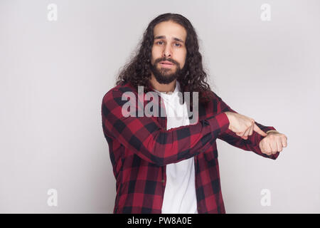 Non abbiamo più tempo. grave uomo con barba nera e lunghi capelli ricci in stile casual, a scacchi maglietta rossa che mostra permanente volta gesto e preoccuparsi. i Foto Stock