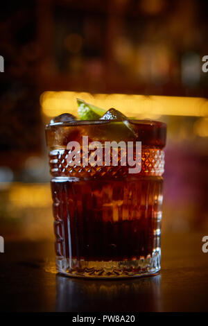 Elevato angolo di visione di un bicchiere di Cuba Libre cocktail con rum, coke, il succo di limone e cubetti di ghiaccio Foto Stock