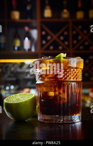 Elevato angolo di visione di un bicchiere di Cuba Libre cocktail con rum, coke, il succo di limone e cubetti di ghiaccio Foto Stock