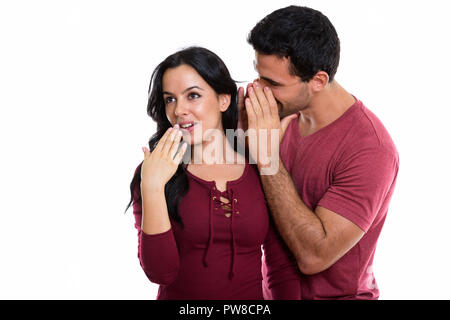 Studio shot di giovani felice coppia sorridente con uomo a bisbigliare Foto Stock