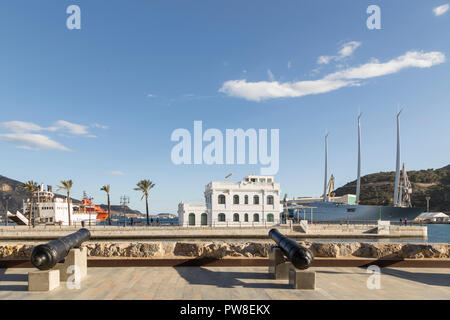 Vista parziale del porto di Cartagena, cannoni in primo piano rivolta verso l'acqua, edificio al centro dell'immagine, Murcia, Spagna Foto Stock