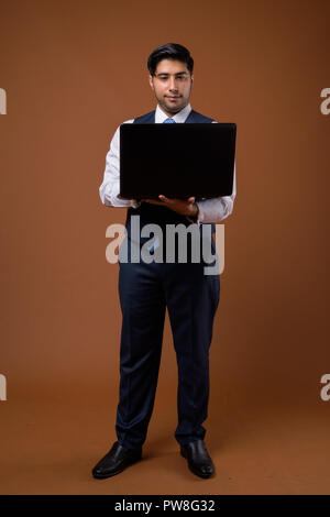 Bel giovane imprenditore iraniano contro lo sfondo marrone Foto Stock