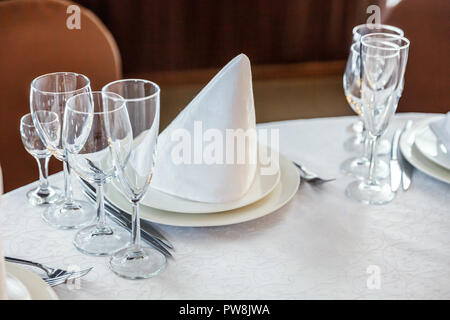 Bicchieri, fiori, forcella, coltello, un tovagliolo piegato in una forma a piramide, serviti a cena nel ristorante con interni accoglienti. Decorazioni per matrimoni e gli elementi per i prodotti alimentari, Foto Stock