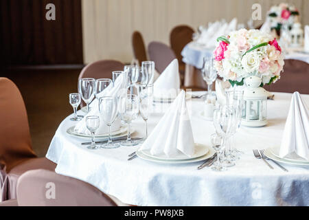 Bicchieri, fiori, forcella, coltello, un tovagliolo piegato in una forma a piramide, serviti a cena nel ristorante con interni accoglienti. Decorazioni per matrimoni e gli elementi per i prodotti alimentari, Foto Stock