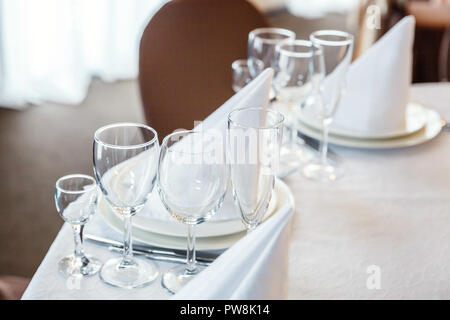 Bicchieri, fiori, forcella, coltello, un tovagliolo piegato in una forma a piramide, serviti a cena nel ristorante con interni accoglienti. Decorazioni per matrimoni e gli elementi per i prodotti alimentari, Foto Stock