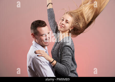 Funny sorridente coppia giovane in posa di studio sfondo rosa Foto Stock