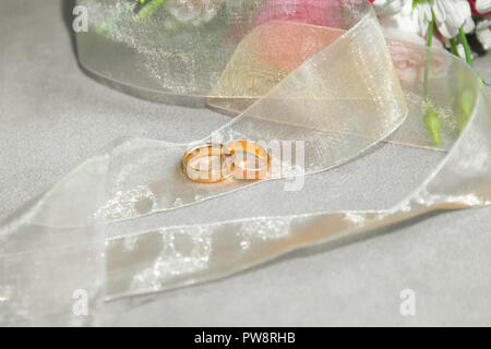 Gli anelli di nozze vicino al naturale bouquet di rose sullo sfondo Foto Stock