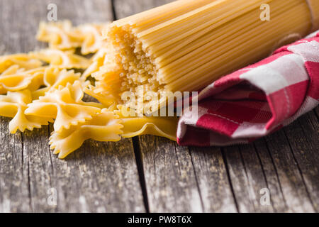 Gli spaghetti e farfalle di pasta sul vecchio tavolo in legno. Foto Stock