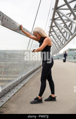 Donna controllando la frequenza cardiaca utilizzando Smartwatch dopo allenamento sul ponte Foto Stock