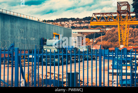 Un magazzino per i tubi di acciaio con un pianale parcheggiato all'esterno Foto Stock