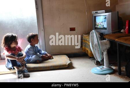 (181013) -- Damasco, ottobre 13, 2018 (Xinhua) -- Foto scattata il 8 ottobre, 2018 mostra i nipoti di 50-anno-vecchio Samar Sbeini guardando un cartoon in TV nella loro casa della nonna nella città di Kafr Batna nell'orientale Ghouta campagna di Damasco, Siria. Persone in Kafr Batna e altre aree di Ghouta orientale era rimasta per anni senza elettricità fino a quando l'esercito siriano liberata la regione da ribelli lo scorso maggio. Il governo siriano ha iniziato ad esercitare sforzi per il risanamento delle zone. Ora il 70 per cento dell'elettricità è stata indietro per le aree popolate nell est Ghouta, secondo t Foto Stock