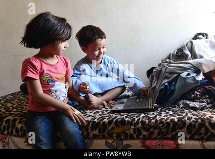 (181013) -- Damasco, ottobre 13, 2018 (Xinhua) -- Foto scattata il 8 ottobre, 2018 mostra i nipoti di 50-anno-vecchio Samar Sbeini usando un computer portatile nella loro casa della nonna nella città di Kafr Batna nell'orientale Ghouta campagna di Damasco, Siria. Persone in Kafr Batna e altre aree di Ghouta orientale era rimasta per anni senza elettricità fino a quando l'esercito siriano liberata la regione da ribelli lo scorso maggio. Il governo siriano ha iniziato ad esercitare sforzi per il risanamento delle zone. Ora il 70 per cento dell'elettricità è stata indietro per le aree popolate nell est Ghouta, secondo un eleggere Foto Stock