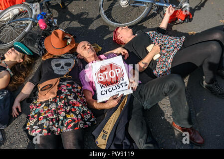 Londra, Regno Unito. 13 ottobre 2018. Persone, compresi Donnachadh McCarthy (in maglia rosa) di smettere di uccidere i ciclisti prendere parte in una decina di minuti di die-in fuori il Parlamento alla fine della processione funebre di ciclisti dietro a cavallo funebre per evidenziare il fallimento dei governi di tutte le principali parti di prendere azione completa su safer escursioni in bicicletta. Smettere di uccidere i ciclisti call per £ 3 miliardi di un anno per essere investito in un protetto nazionale di ciclismo e di rete per azioni urgenti per ridurre gli effetti tossici inquinamento atmosferico da emissioni dei motori diesel e i veicoli a benzina che uccide decine di migliaia di persone ogni anno, e Foto Stock