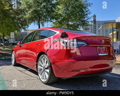 Rosso Modello Tesla tre (3), la sosta e la carica a un veicolo elettrico o auto elettrica stazione di ricarica su strada a Montgomery in Alabama, Stati Uniti d'America. Foto Stock