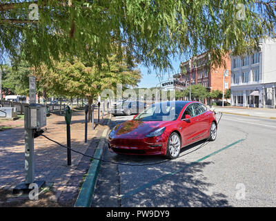 Rosso Modello Tesla tre (3), la sosta e la carica a un veicolo elettrico o auto elettrica stazione di ricarica su strada a Montgomery in Alabama, Stati Uniti d'America. Foto Stock