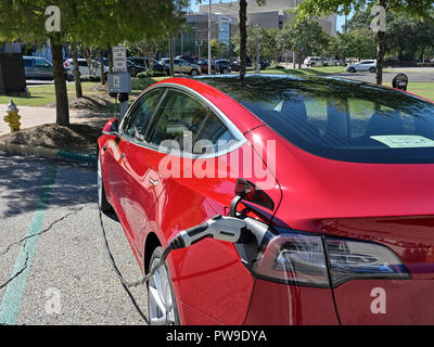 Rosso Modello Tesla tre (3), la sosta e la carica a un veicolo elettrico o auto elettrica stazione di ricarica su strada a Montgomery in Alabama, Stati Uniti d'America. Foto Stock