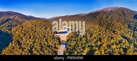 Elevata ampio panorama di Guthega diga sul fiume nevoso in montagne innevate durante la stagione invernale quando distanti picchi sono sotto il bianco della neve. Neve spessa-gum t Foto Stock