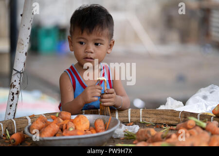 Un giovane ragazzo filippino dietro un vegetale in stallo.