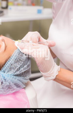 Persone e cosmetologia nozione - Stretta di mano di esperti estetista iniettare botox nelle femmine di fronte. Foto Stock