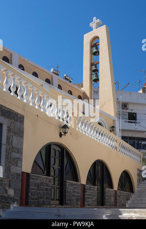 Belfry nella parte moderna della città. Tre campane ed una croce sulla cima della torre. Azzurro cielo. Agios Nikolaos, Creta, Grecia. Foto Stock