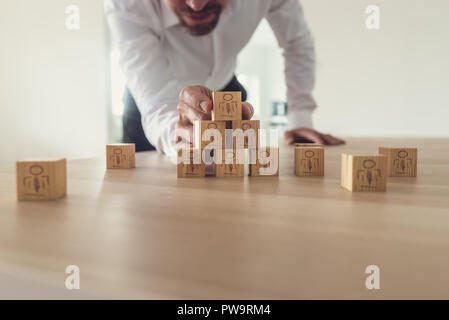 Business executive di impilamento di cubi di legno con le persone le icone sulla scrivania in ufficio. Concettuale del team aziendale e risorse umane, retro per effetto del filtro. Foto Stock