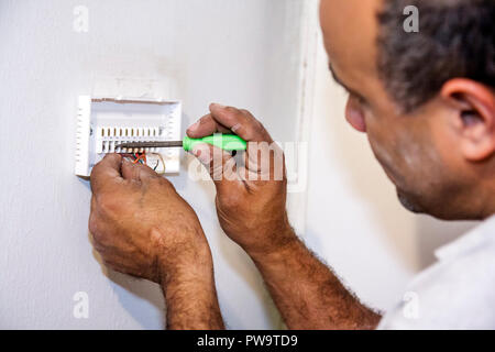 Miami Beach Florida, aria condizionata, meccanico, lavoratore, lavoratori, riparatori, termostato digitale, installazione, installazione, riparazione, filo, strumento, uomo ispanico uomini maschio Foto Stock