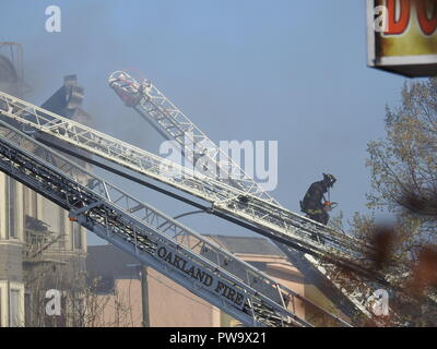 Un pompiere sale una scala mentre combatte un fuoco mortale in una casa a metà strada a San Pablo Ave. 2551 a Oakland il 27 marzo 2017. Foto Stock