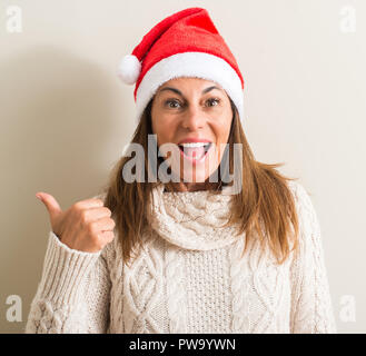 Medioevo donna che indossa il natale di santa claus hat rivolto con la mano e il dito verso l'alto con la faccia felice sorridente Foto Stock