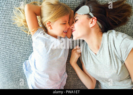 Tenere premuto è stretto. Carino amorevole donna emotiva abbracciando la figlia stretto mentre la spesa la mattina a letto e sentirsi felice. Il naso a naso Foto Stock