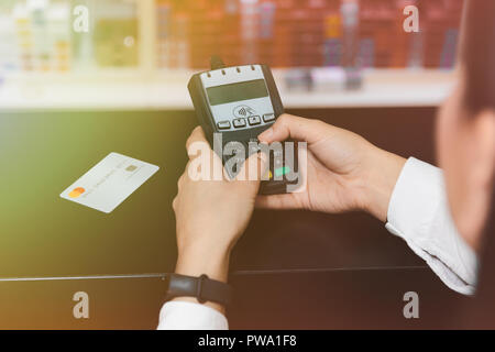 Vicino la mano della donna di mani di inserire il codice pin sul terminale carte di credito. Foto Stock