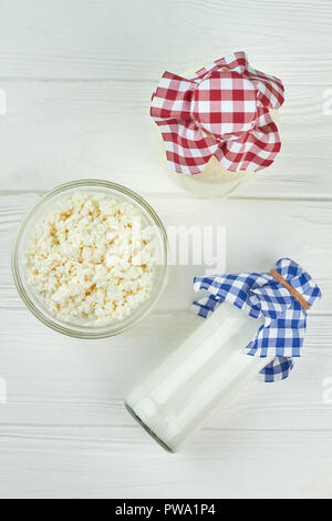 Prodotti lattiero-caseari su sfondo bianco. Vista superiore sulle bottiglie di vetro con latte, yogurt e una ciotola di fresco formaggio cottage. Cibo sano concetto. Foto Stock