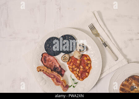 Inglese fry up colazione sulla piastra bianca e sfondo rustico Foto Stock